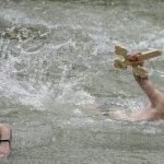 Traditii de Boboteaza barbati sarind in apa si fete cu busuioc